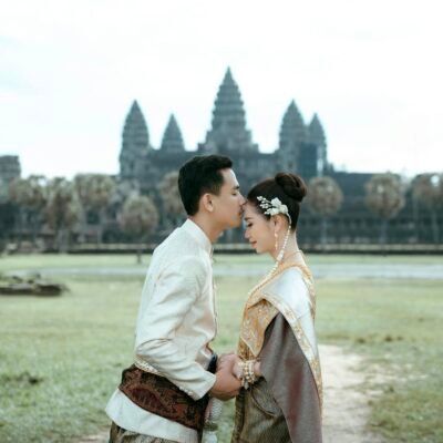 A couple in traditional clothing standing in front of a temple